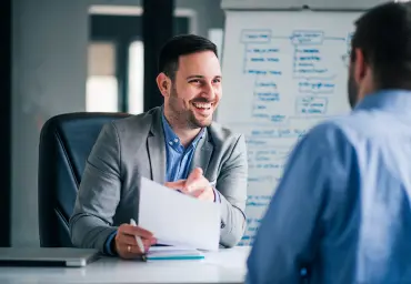 Recruiter Interviewing a Candidate in a Professional Office Smiling recruiter conducting an interview with a candidate in a professional office setting, holding documents