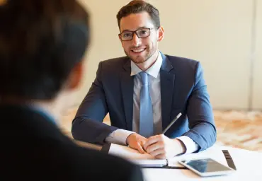 Professional Recruiter Interviewing a Candidate Smiling recruiter in a blue suit conducting an interview with a candidate, taking notes on a notepad in a professional setting
